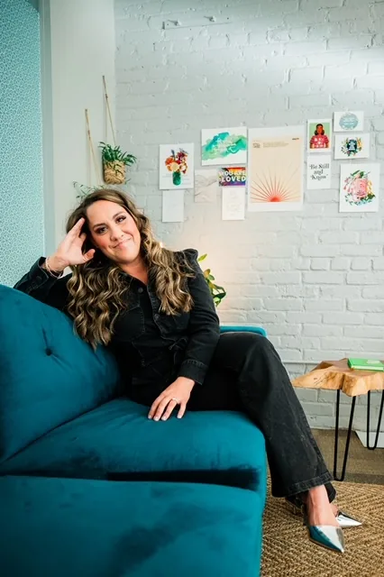 Dr. Lily Zehner seated on a teal velvet couch in her Denver office