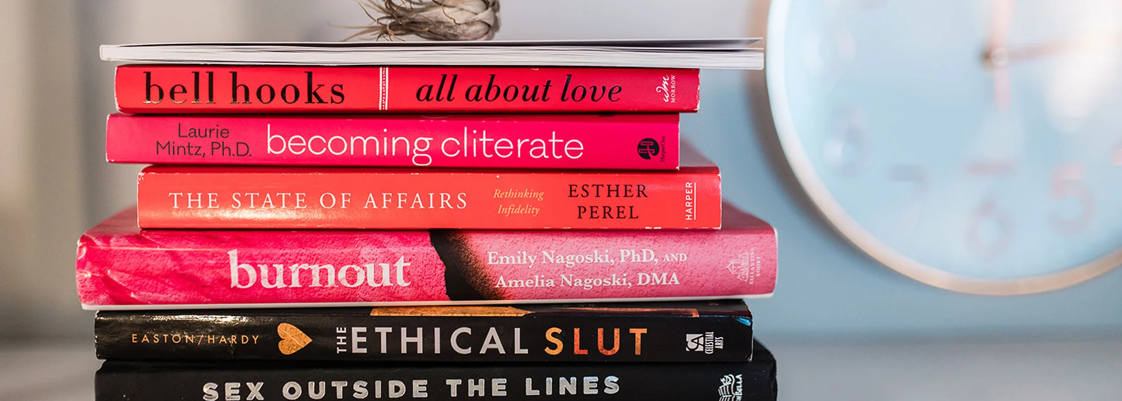 A stack of books in Dr. Lily Zehner's office including All About Love, Becoming Cliterate and My Grandmother's Hands