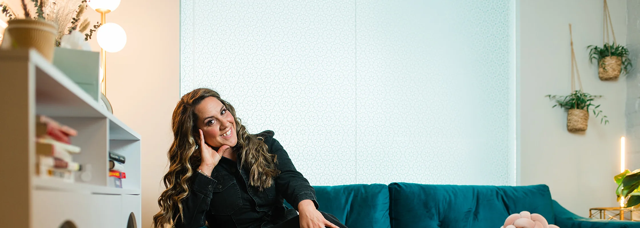 Dr. Lily Zehner seated beside the teal velvet couch in her Denver therapy office